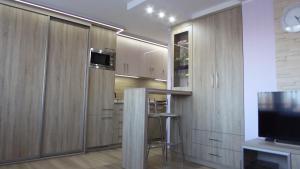 グディニャにあるApartament Mario Skwer Kościuszkiの木製のキャビネットとバー付きのキッチンが備わります。