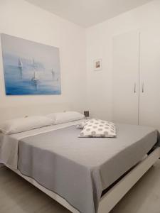 uma cama num quarto branco com uma fotografia na parede em Casetta Cirantò monolocale em Ischia