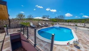 a large swimming pool on a patio with chairs around it at Villa Plavota in Ljubuški