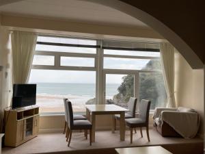 sala de estar con mesa, sillas y ventana grande en Redcliffe Apartments Flat 7A en Swansea