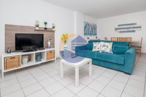 sala de estar con sofá azul y TV en Apartamentos Encosta da Marina - Praia da Rocha, en Portimão
