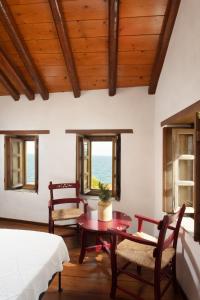 una camera con tavolo, sedie e finestre di Rodi House a Monemvasía