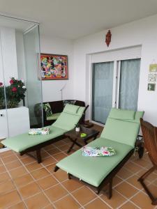 Habitación con 2 sillas verdes y sofá en Mi Capricho, en Sitio de Calahonda