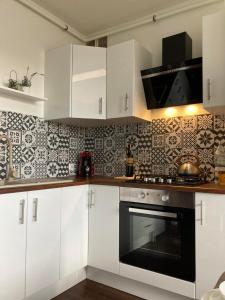 a kitchen with white cabinets and a black oven at Apartament Miodowa 9 in Zwierzyniec