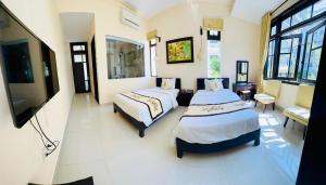 um quarto com 2 camas e uma televisão de ecrã plano em Hoi An Cottage Villa em Hoi An