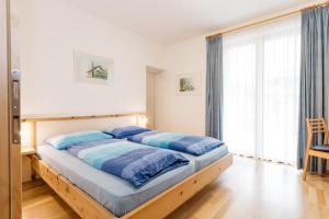 Schlafzimmer mit einem Bett mit blauer Bettwäsche und einem Fenster in der Unterkunft Appartement Florian in Kaltern