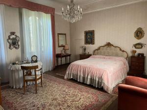 a bedroom with a bed and a table and a chandelier at CASA LA TORRE un castello alle porte di Firenze in Florence
