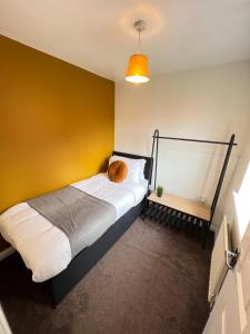 a bed in a room with a yellow wall at Spacious 3-Bedroom house with 5 beds and sofa-bed in Manchester
