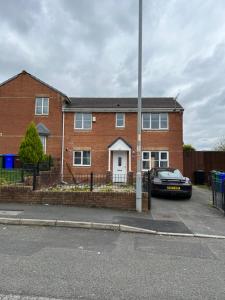 a brick house with a car parked in a parking lot at Spacious 3-Bedroom house with 5 beds and sofa-bed in Manchester