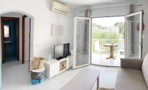 a white living room with a tv and a couch at Apartamento playa 2 Fassers piscina Port Pollensa in Port de Pollensa