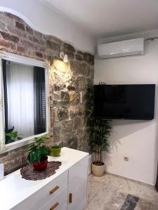 a living room with a stone wall and a tv at Apartment Vitturina in Kaštela