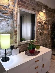 a white dresser with a mirror and a lamp on it at Apartment Vitturina in Kaštela
