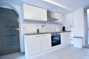 a white kitchen with white cabinets and an oven at Souterrain apartment in Wesseling in Wesseling