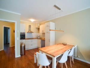eine Küche mit einem Holztisch und weißen Stühlen in der Unterkunft Dünenpark Binz - Komfortplus Ferienwohnung mit 2 Schlafzimmern und Terrasse 187 in Binz