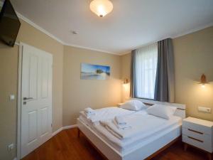 ein Schlafzimmer mit einem Bett mit weißen Laken und einem Fenster in der Unterkunft Dünenpark Binz - Komfortplus Ferienwohnung mit 2 Schlafzimmern und Terrasse 187 in Binz
