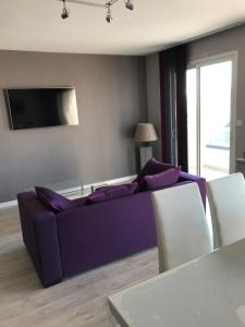 uma sala de estar com um sofá roxo e uma televisão em APPARTEMENT Résidence GARDENIAS SAINT JEAN DE MONTS em Saint-Jean-de-Monts