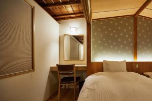 Un dormitorio con una cama, un escritorio y una silla. en Gion Shirakawa no Yado, en Kioto