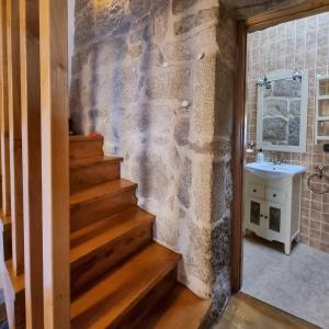 baño con pared de piedra, escalera y lavabo en Casa mariñeira San Tomé, en Cambados