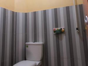 a bathroom with a toilet and a striped wall at Sisca Homestay Tidung RedPartner in Kepulauan Seribu