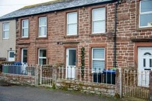 a brick house with a fence in front of it at Unique House - Leisure - Garden - Lake District in Wigton