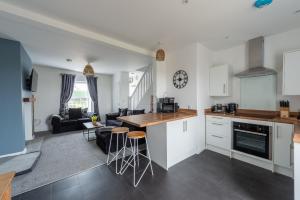a kitchen and living room with a counter and stools at Unique House - Leisure - Garden - Lake District in Wigton
