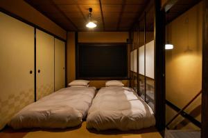 Duas camas grandes num quarto com uma janela em YADORU KYOTO HANARE Kanade No Yado em Quioto