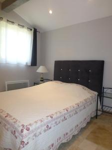 a bedroom with a bed with a white bedspread and a window at Le Gîte du Moulin in Sarrians