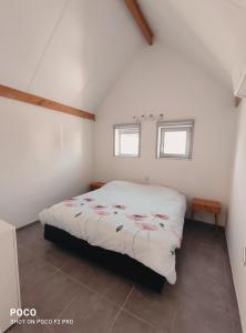 ein Schlafzimmer mit einem Bett in einem Zimmer mit zwei Fenstern in der Unterkunft Vakantiewoning Polderhuis 10, airco en verwarming in alle kamers, privé parkeerplaats en afgesloten tuin in Koksijde