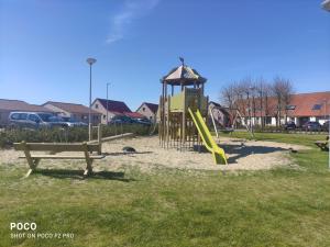 een park met een speeltuin met een glijbaan en een bank bij Vakantiewoning Polderhuis 10, airco en verwarming in alle kamers, privé parkeerplaats en afgesloten tuin in Koksijde