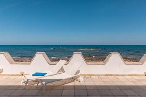 a beach with a white bench and the ocean at La Porta del Mare in Villanova di Ostuni