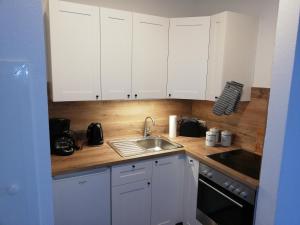 a kitchen with white cabinets and a sink at Ferienwohnung Hafensicht 25507 in Weener +8 photos