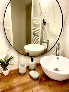 La salle de bains est pourvue d'un lavabo blanc et d'un miroir. dans l'établissement Joli T4 rénové climatisé entre St Charles/le Vieux-port, à Marseille