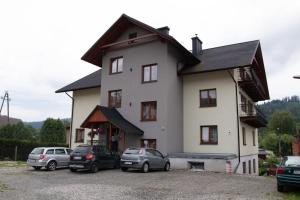 a large white house with cars parked in front of it at Apartamenty Pokoje Lawenda Wisła in Wisła