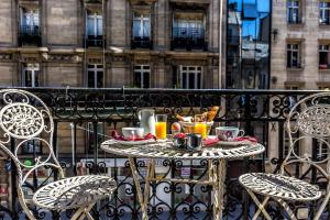 einen Tisch mit Speisen und Getränken auf dem Balkon in der Unterkunft Hotel Regence Paris in Paris