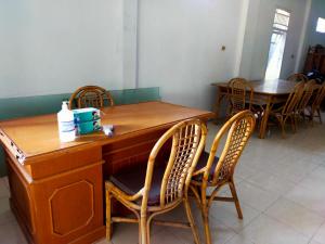 a wooden desk with chairs and a table in a room at Ombai Guest House 27 Syariah Mitra RedDoorz in Kertapati