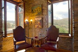 two chairs and a table in a room with windows at The House of Prince in Nea Stira