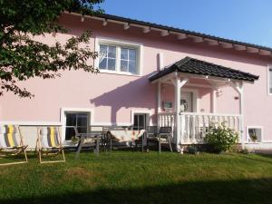 een roze huis met stoelen en een tafel in de tuin bij Schöne Moderne Wohnung in Hannoversch Münden