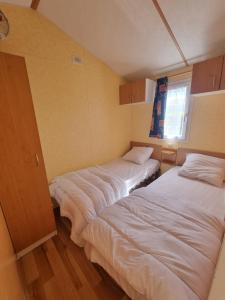 duas camas num quarto com lençóis brancos em La belle Perrochoise 13 mobilhome em La Cotinière
