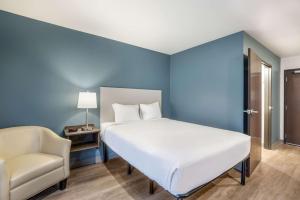 ein Schlafzimmer mit einem großen weißen Bett und einem Stuhl in der Unterkunft WoodSpring Suites Gurnee - Chicago in Gurnee