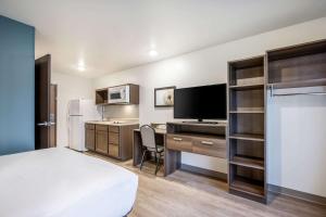Schlafzimmer mit einem Bett und einem Schreibtisch mit einem TV in der Unterkunft WoodSpring Suites Gurnee - Chicago in Gurnee
