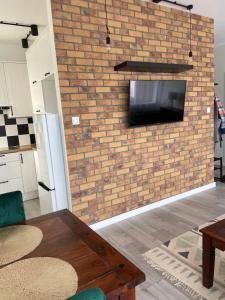 a living room with a brick wall with a flat screen tv at Apartament Dziewiątka in Giżycko