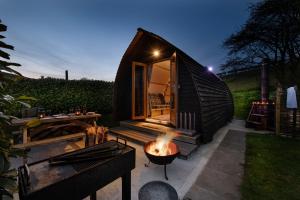 een klein zwart tiny house met een vuurplaats bij Humble Bee Farm Glamping in Folkton