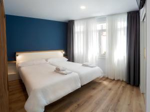 1 dormitorio con cama blanca y pared azul en Casa do cabo, en Arzúa
