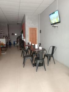 comedor con mesas y sillas y TV de pantalla plana en Rooms at Josapa Guest House, en Batam Centre