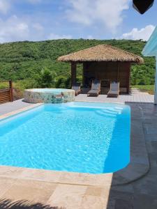 a blue swimming pool with a gazebo at Villa de 4 chambres avec vue sur la mer piscine privee et jacuzzi a Le Marin a 3 km de la plage in Le Marin