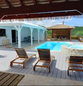 a patio with two chairs and a swimming pool at Villa de 4 chambres avec vue sur la mer piscine privee et jacuzzi a Le Marin a 3 km de la plage in Le Marin