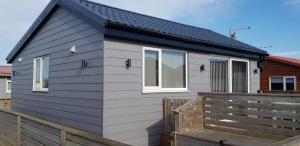 a house with a black roof and a wooden fence at luxury 2-Bed modern chalet in Bridlington in Bridlington