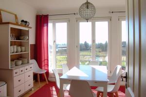 a dining room with a table and chairs and windows at FeWo Uckerseen, 4 Zimmer mit Bad ensuite und Panoramablick in Seehausen
