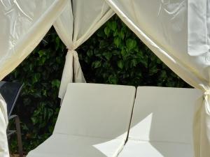 a white tent with a chair in front of a green hedge at Casa Francesca Altea piscina y aparcamiento privado in Altea