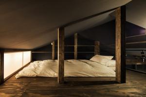 een bed in een donkere kamer met houten palen bij YADORU KYOTO HANARE Washi No Yado in Kyoto